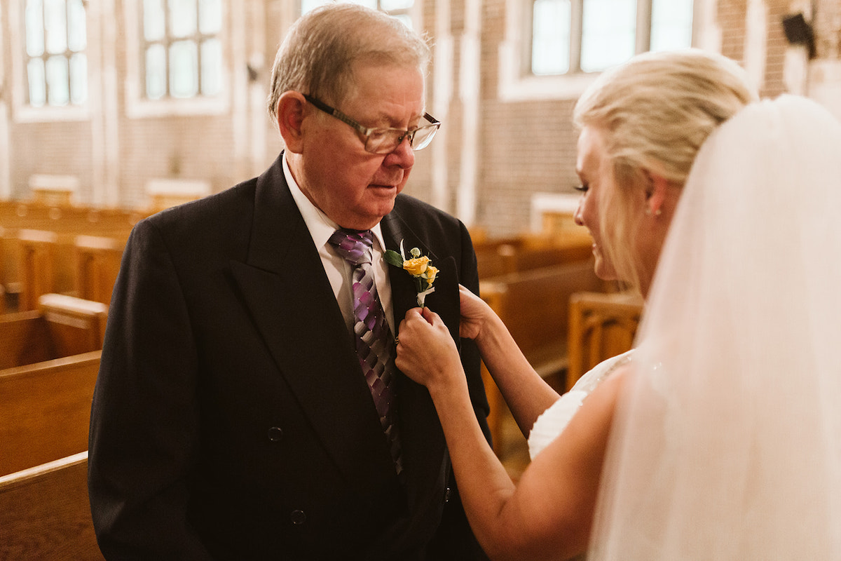 Bride pins a boutonniere on her grandfather's lapel
