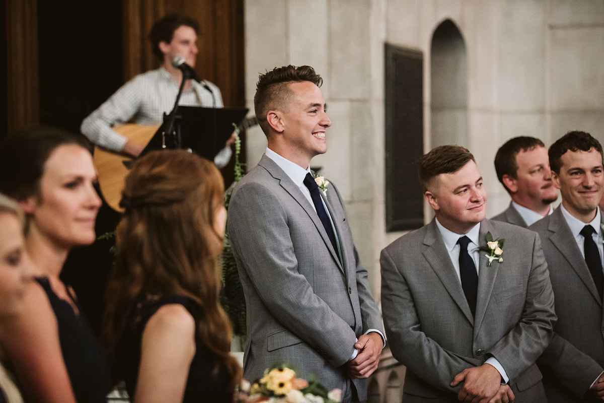 Groom smiles widely and groomsmen look on