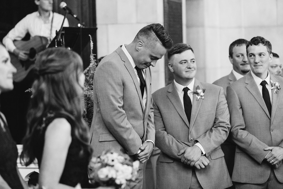 Groom bows his head with emotion and groomsmen look on