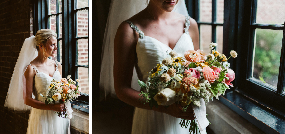 Bride holds large bouquet with yellow, peach, and pink flowers in front of black framed window