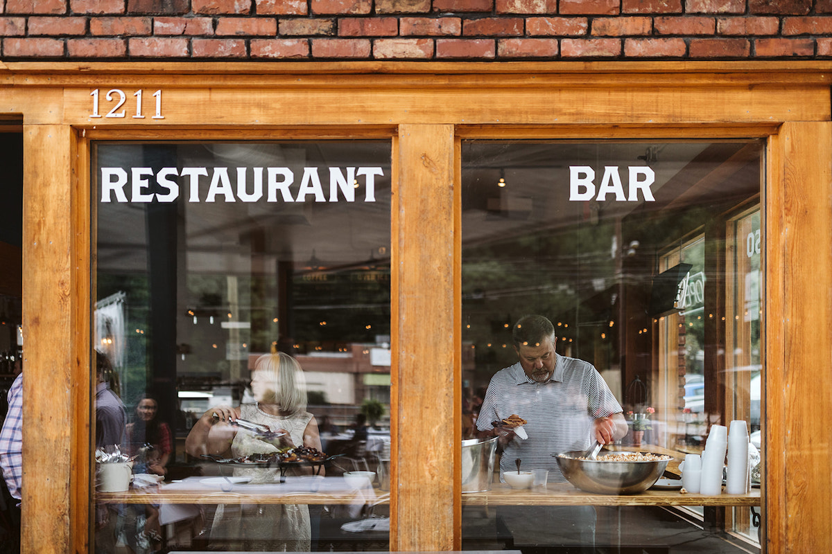 Guests through the large windows of The Daily Ration which have "restaurant" and "bar" painted on them