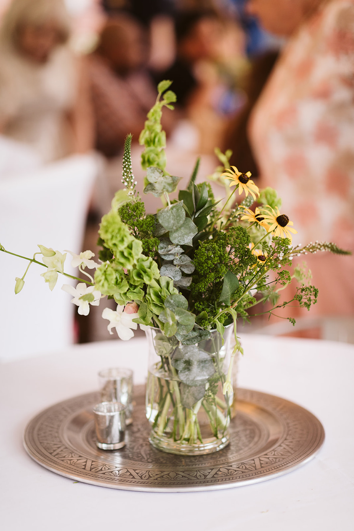 Greenery and Black Eyed Susans in a short vase on a metal platter