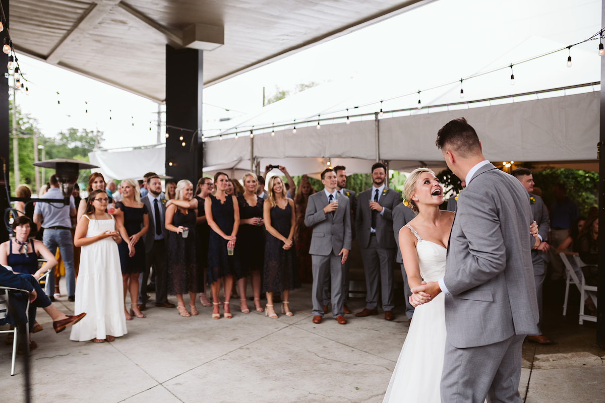 Bride and groom dance under patio cover at The Daily Ration while wedding guests watch
