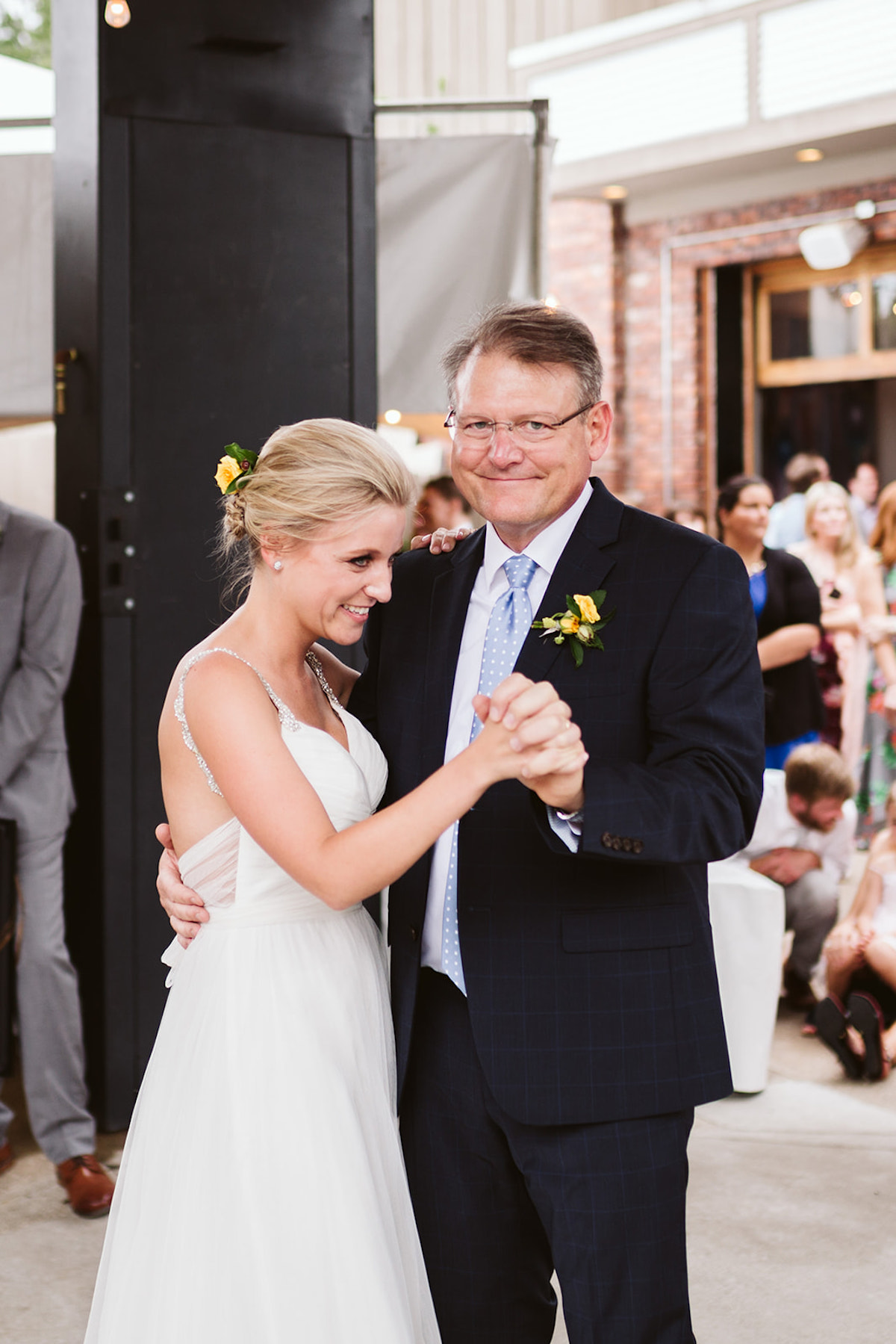 Bride dances with her father, dressed in a dark blue suit and light blue tie.