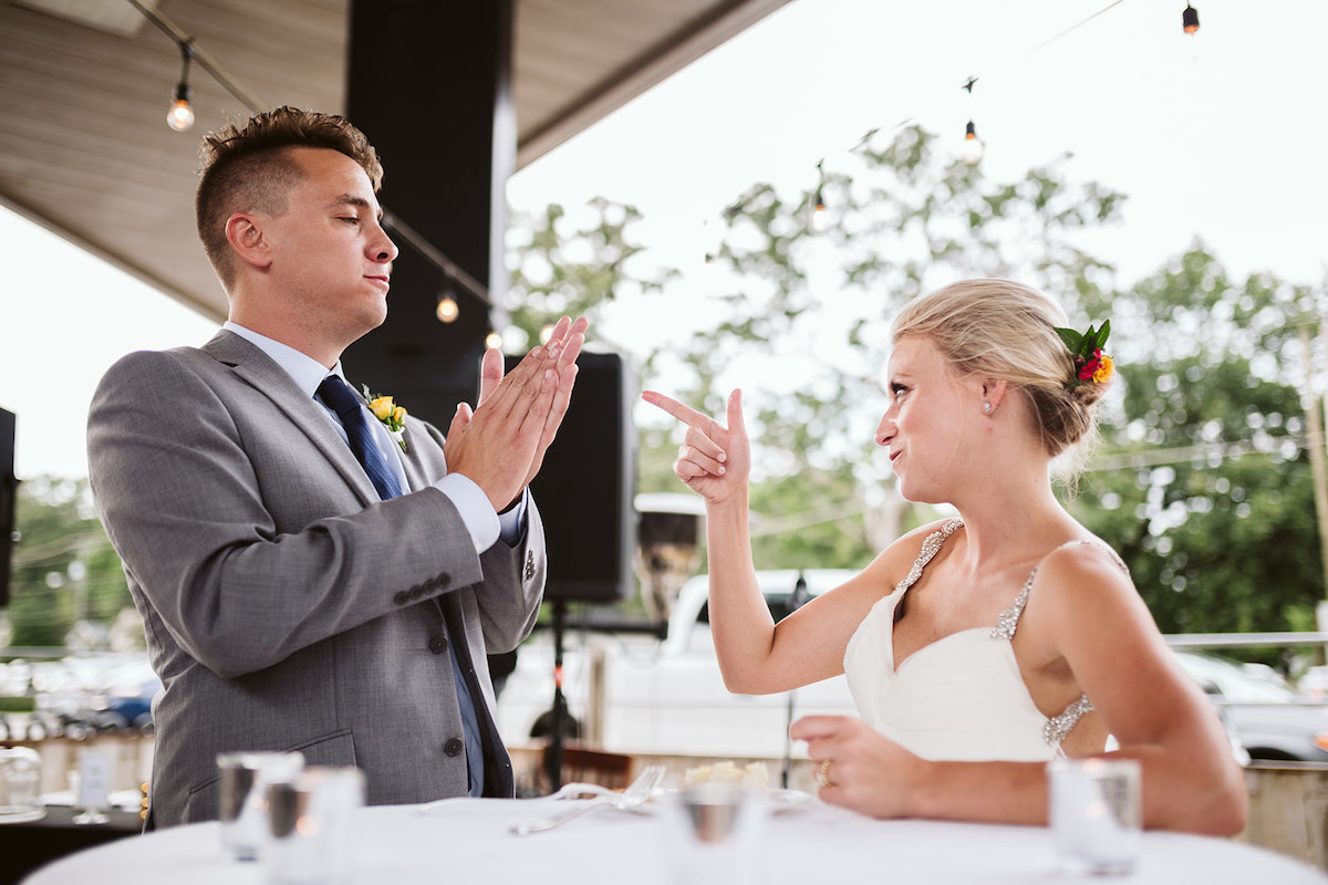 Bride points finger gun at groom while he claps
