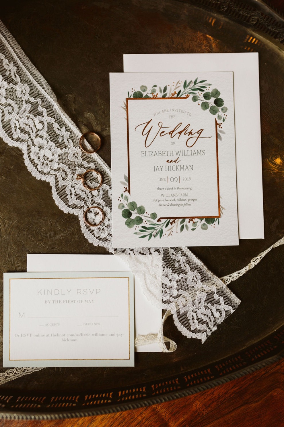 elegant backyard wedding invitations, rings, and lace on a silver tray