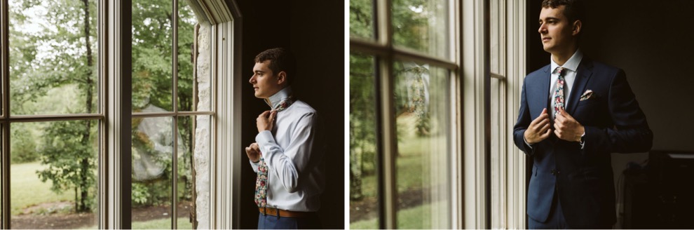 groom putting on tie and suit jacket in front of large windows