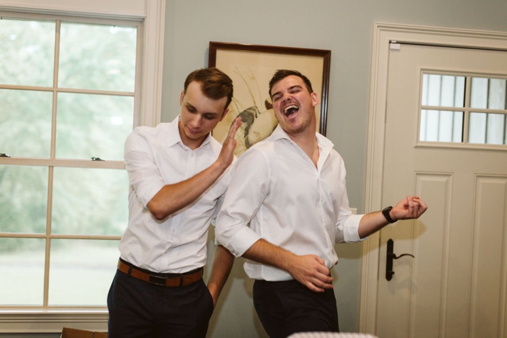 groomsmen goofing off and playing air guitar while getting dressed for ceremony