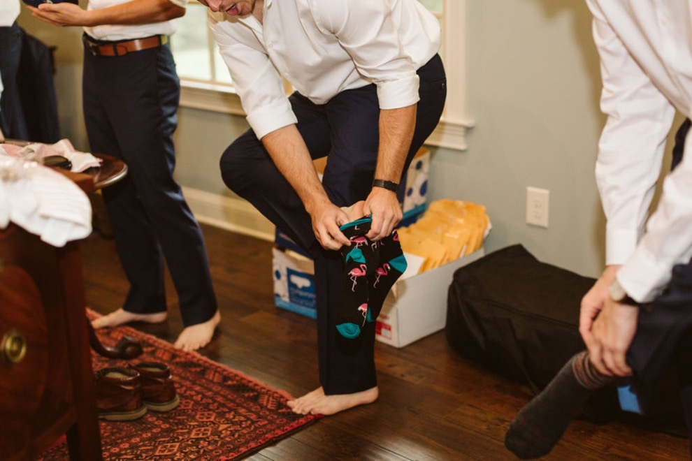 groomsmen putting on colorful socks under dark blue pants