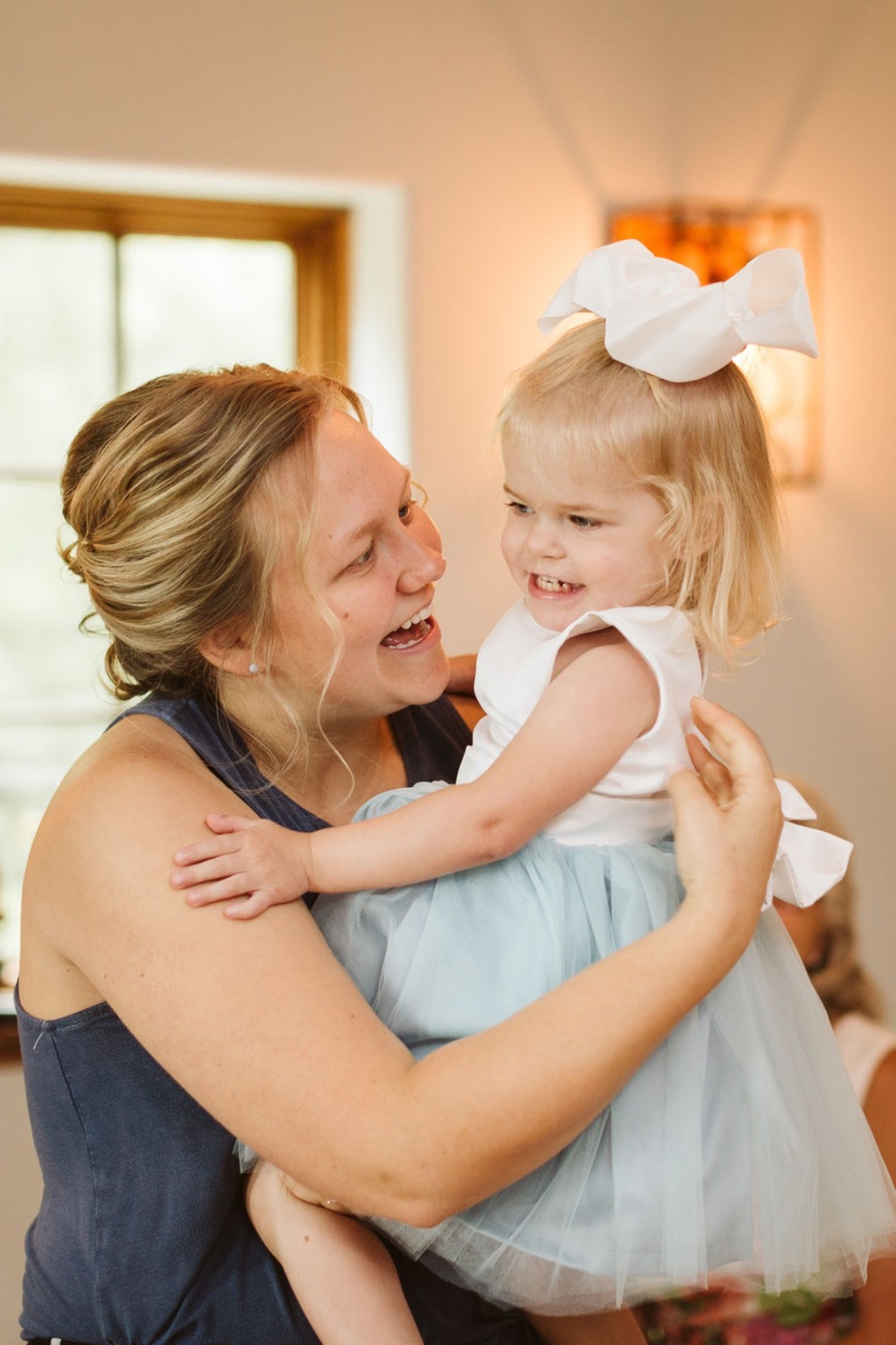 bride holding flower girl in white and blue dress