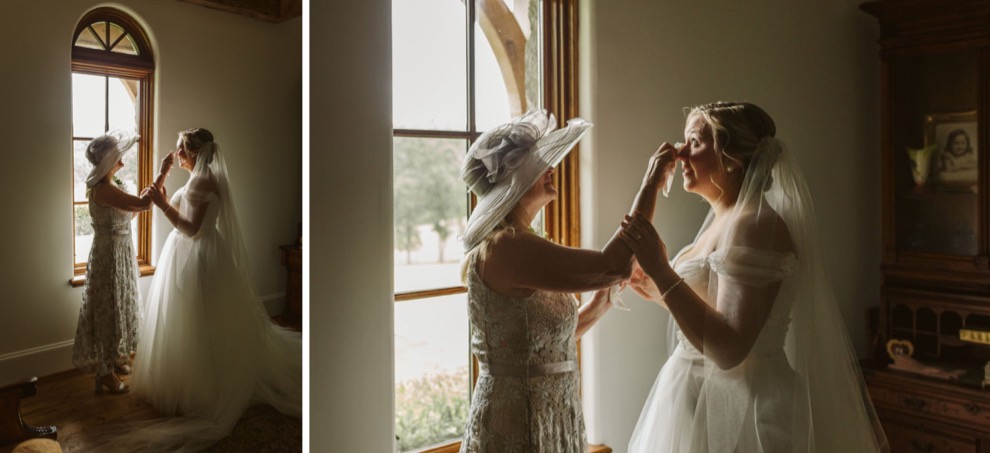 mother dabbing at bride's tears in front of a tall window