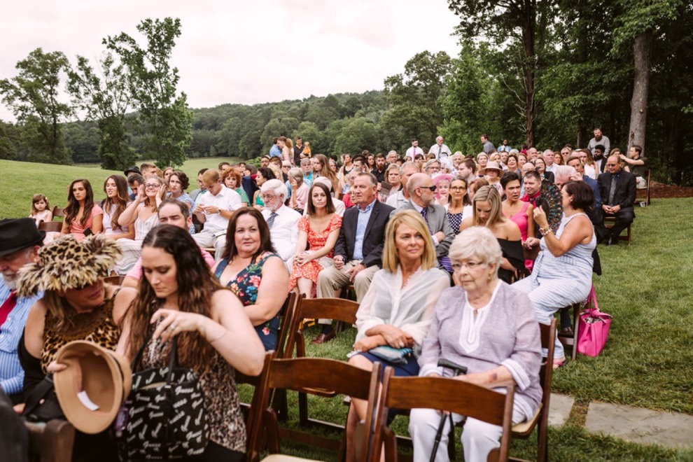 guests seated in wooden folding chairs for outdoor wedding ceremony