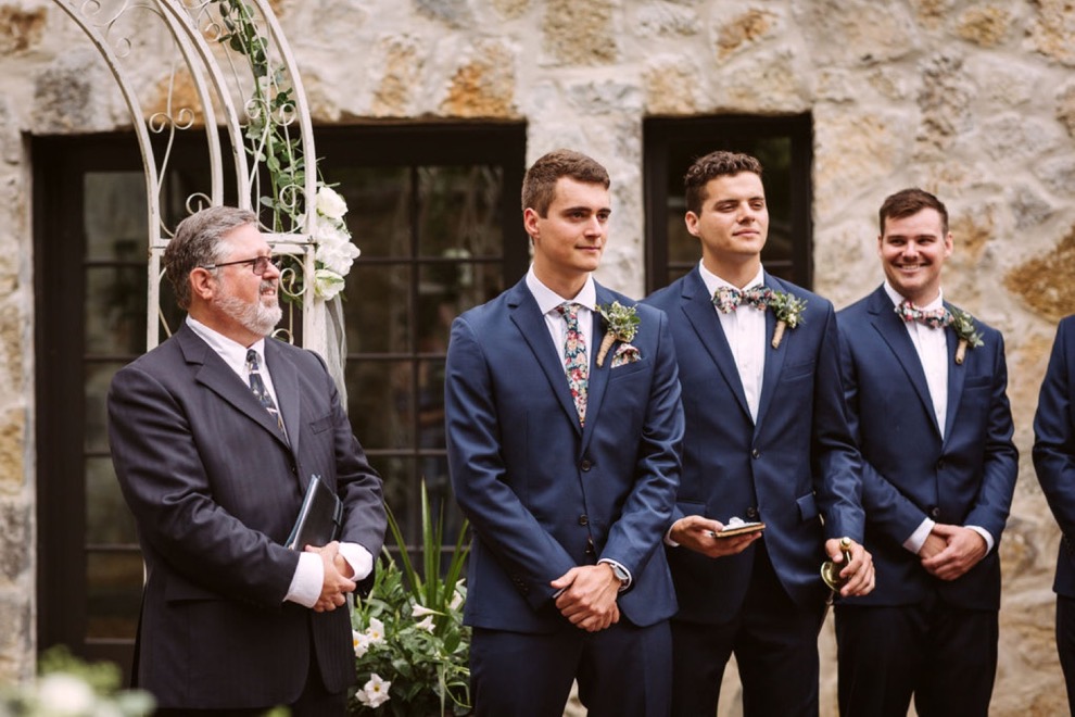 groom and groomsmen watch bride walk down aisle