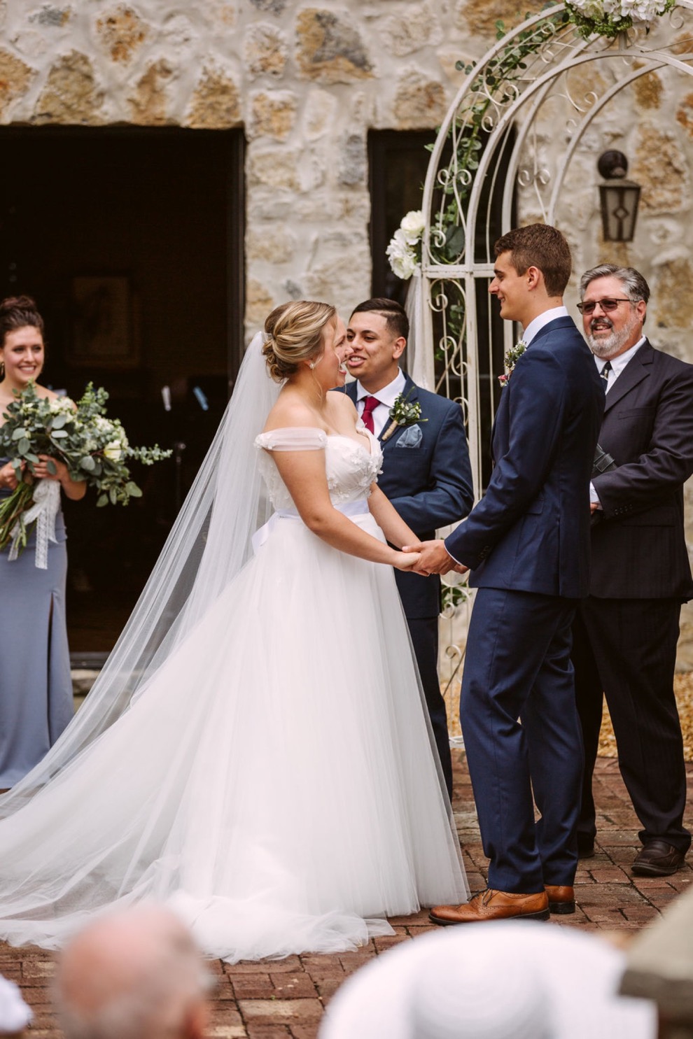 bride and groom holding hands and smiling as officiant greets the wedding guests
