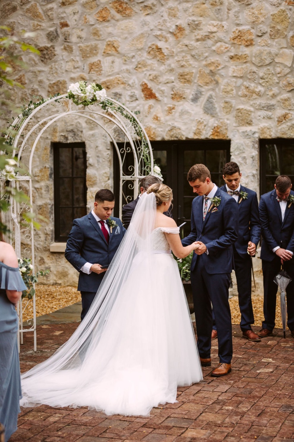 bride and groom bow their heads in prayer during their backyard wedding ceremony
