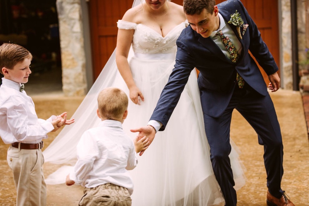 groom reaching down to give ring bearers high fives