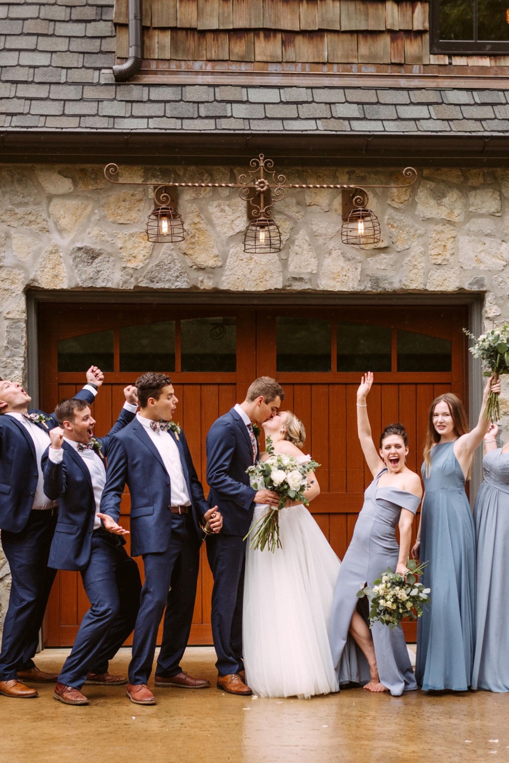 bridal party posing for photos in front of wooden garage doors