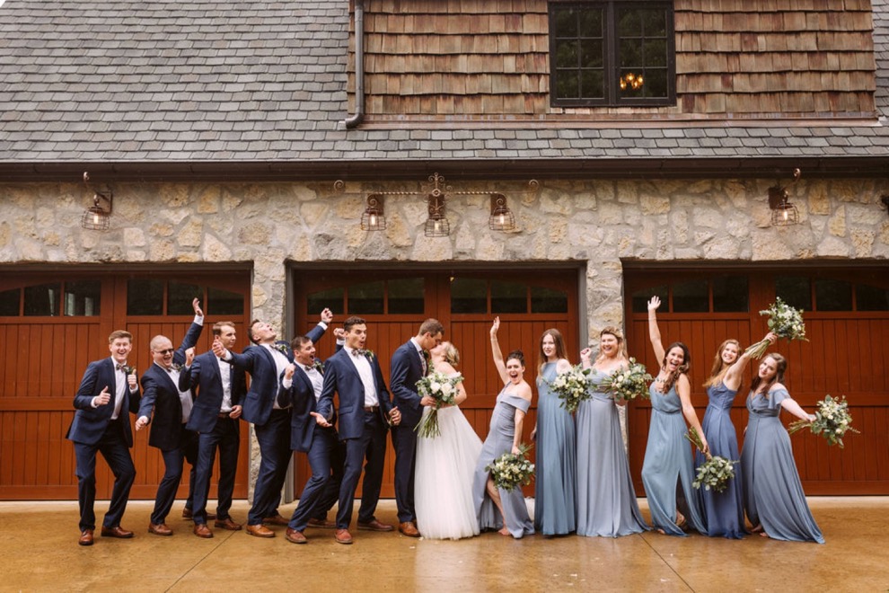 bridal party posing for photos in front of wooden garage doors