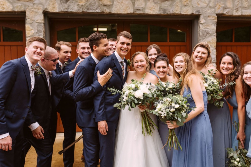 bridal party posing for photos in front of wooden garage doors