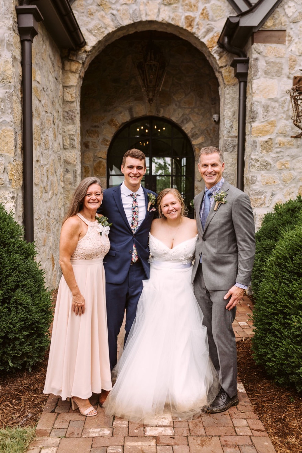 bride and groom posing with family for portraits