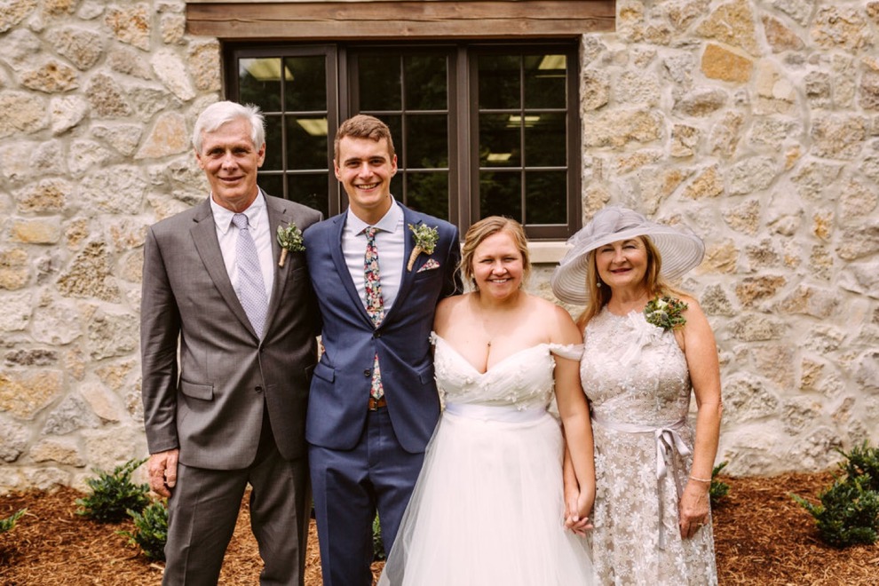 bride and groom posing with family for portraits