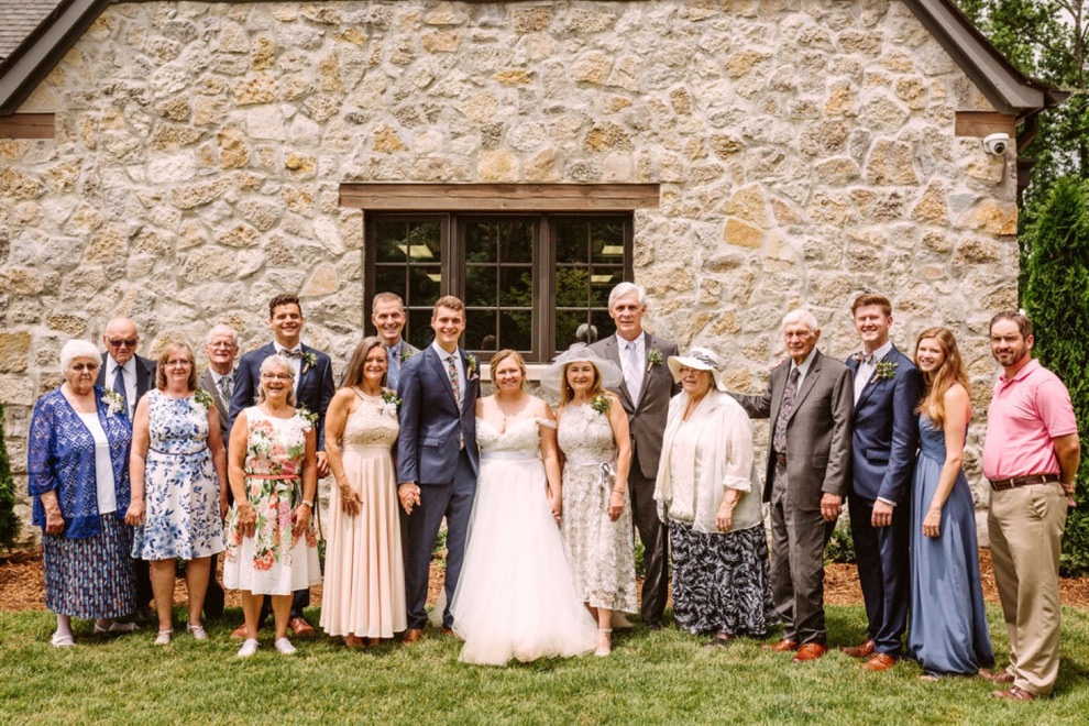 bride and groom posing with family for portraits