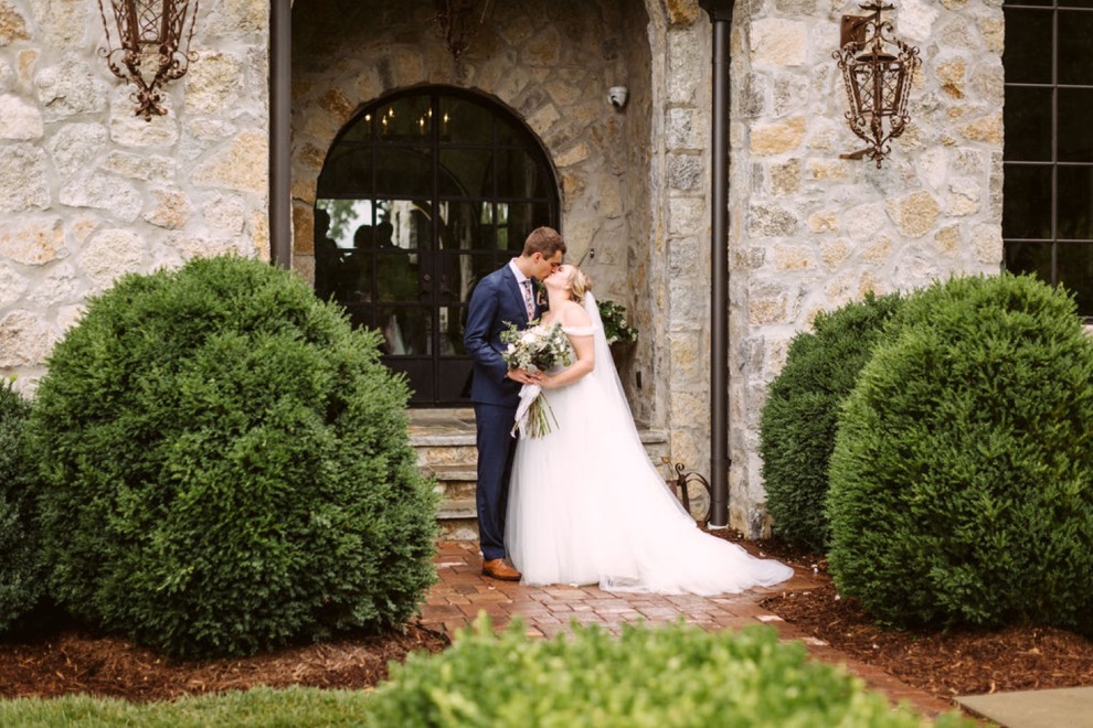 bride and groom kissing on a brick path outside a stone Georgia estate