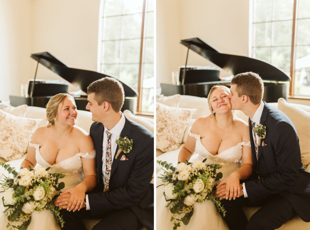 bride and groom sitting on a white couch in front of a grand piano smiling at each other