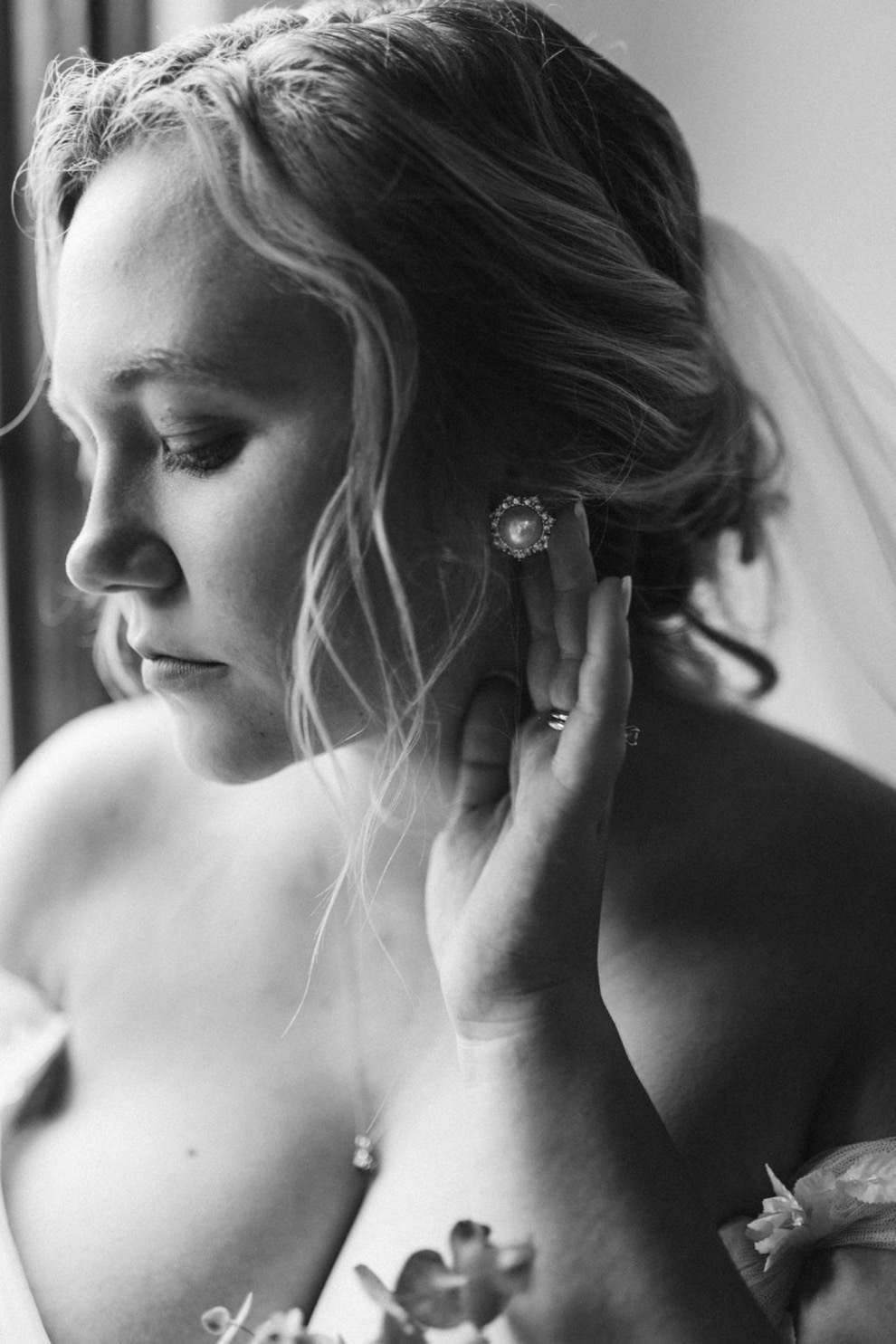 bride fixing her large pearl earrings