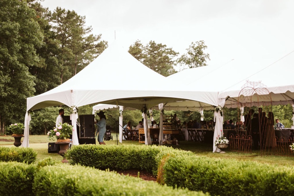 white tent set up on green lawn for backyard wedding