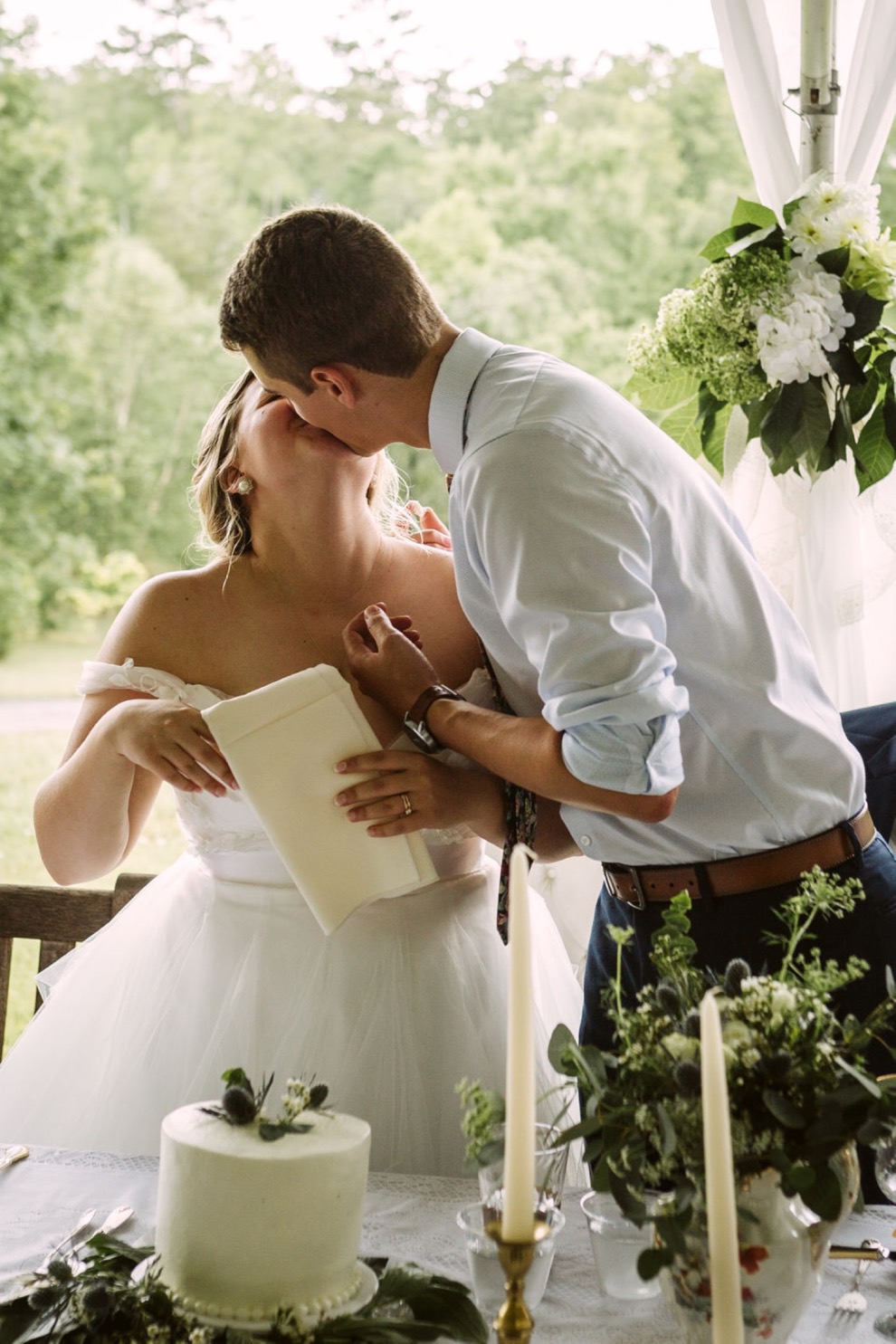 bride and groom kiss in front of cake and candles