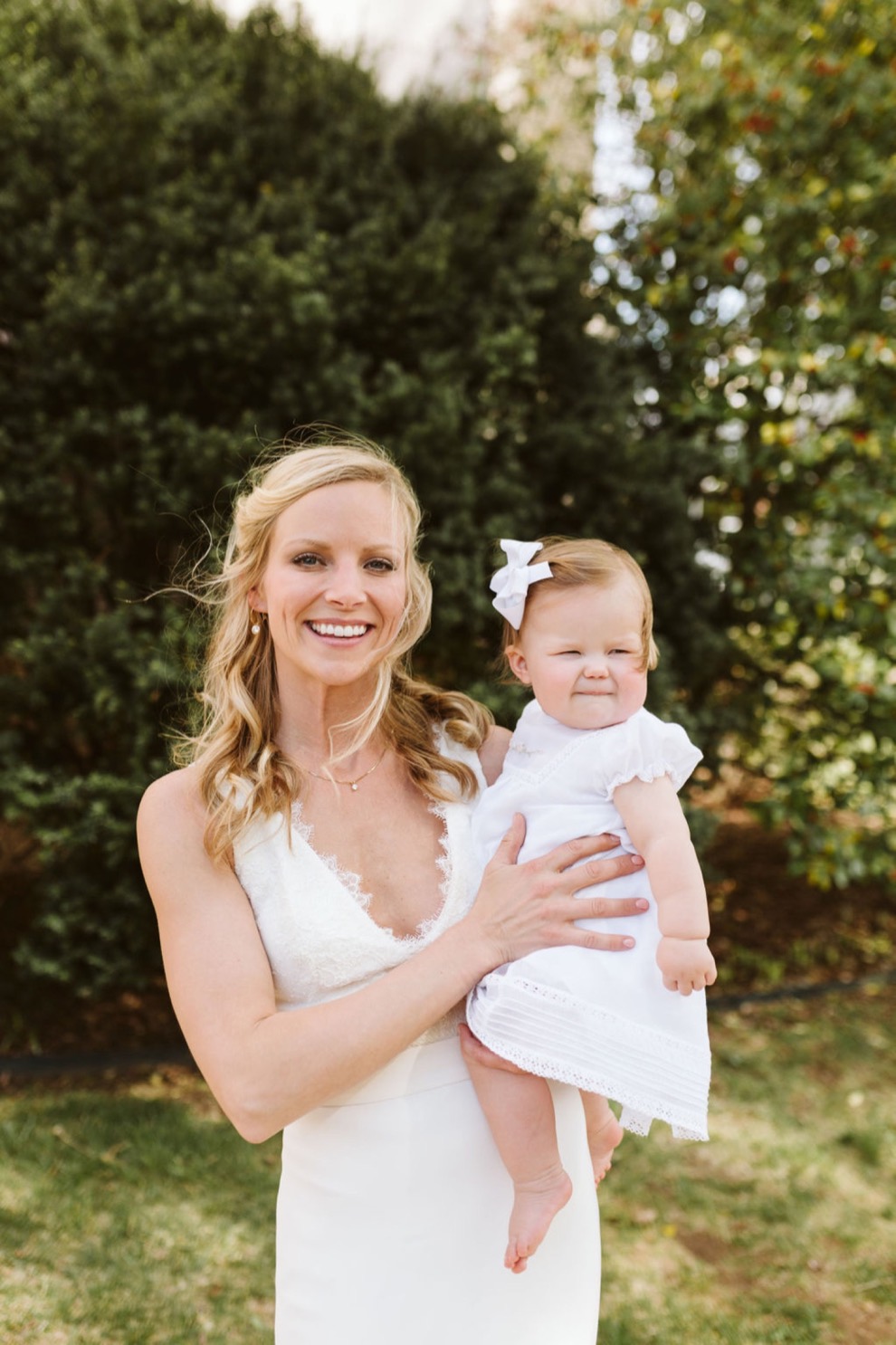 bride holding baby girl in white dress