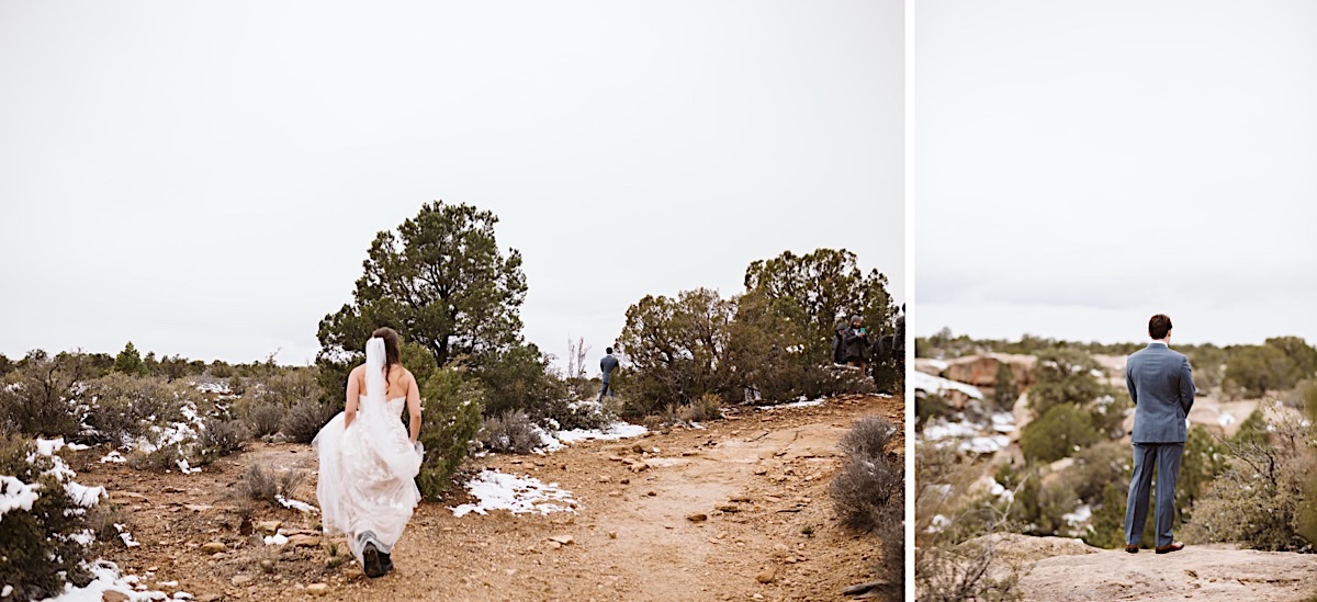 Groom stands overlooking a cliff. Bride walks toward him for their private first look before a snowy Zion elopement ceremony