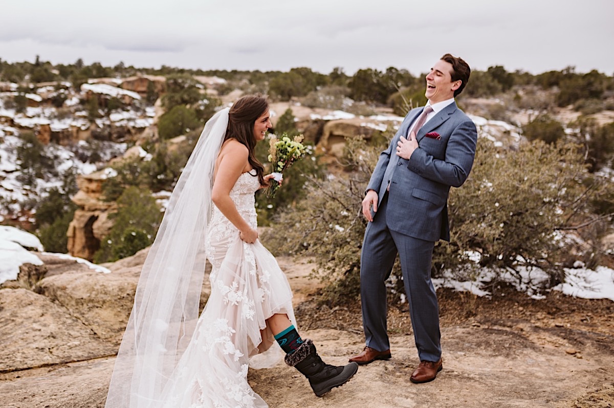 Groom laughs when ride pulls up the hem of her strapless, lacy wedding gown to reveal high wool socks and snow boots.