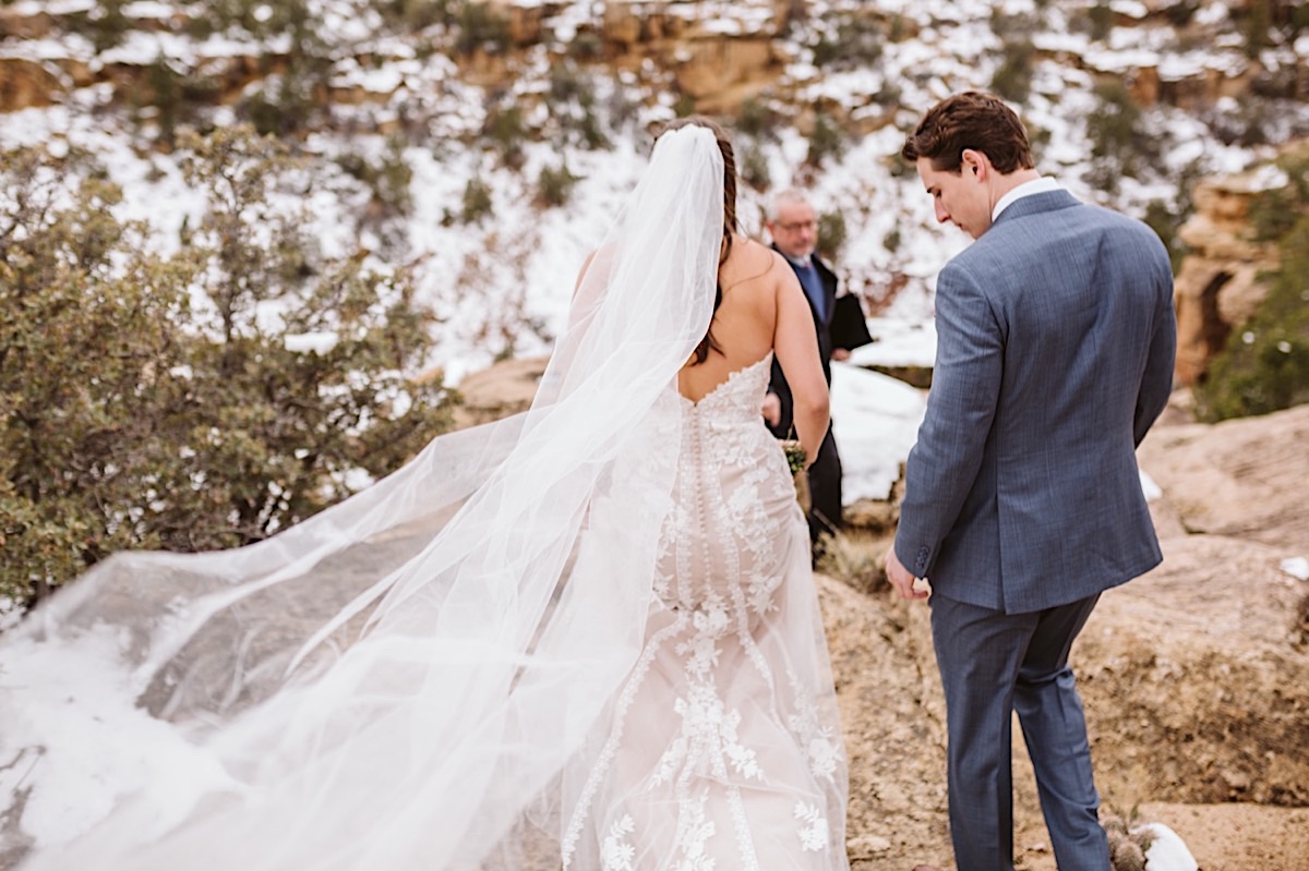 Bride and groom walk to the edge of a cliff to exchange vows, her veil streaming behind her