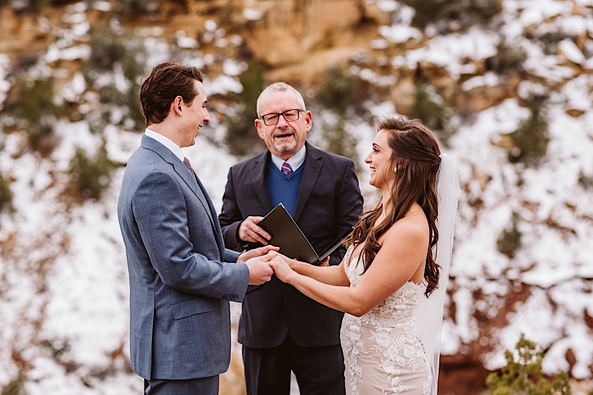 Bride and groom hold hands and exchange vows on a cliffside in Zion
