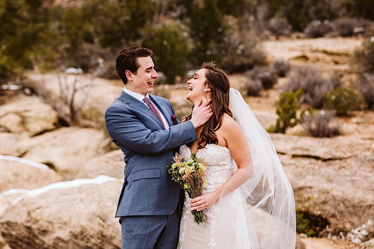 Bride and groom standing close to each other, his hand caress her neck while they laugh