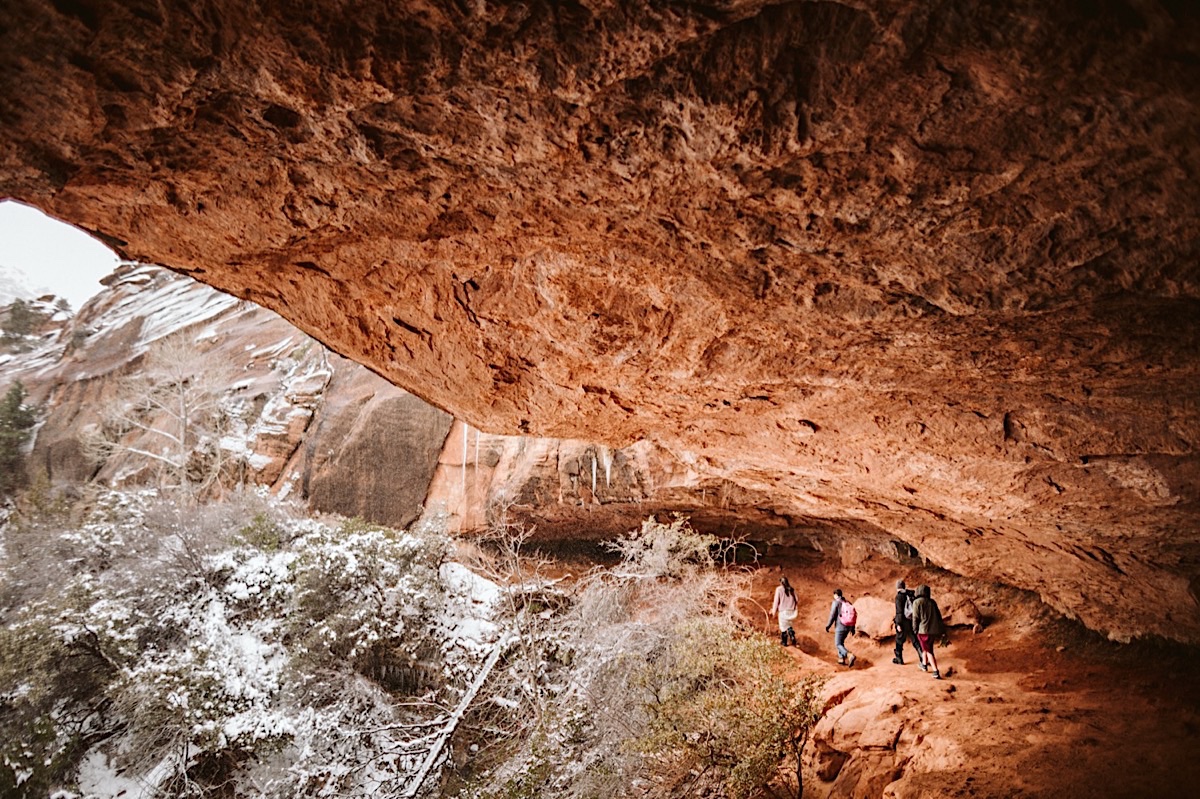 Bridal party hikes under huge red cliffs to Canyon Overlook in Zion National Park