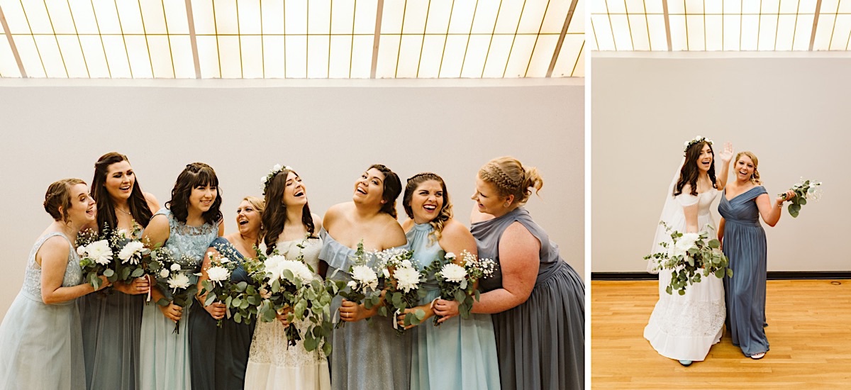 Bride laughing with bridesmaids. They wear various shads of blue and hold white and green bouquets under a skylight.