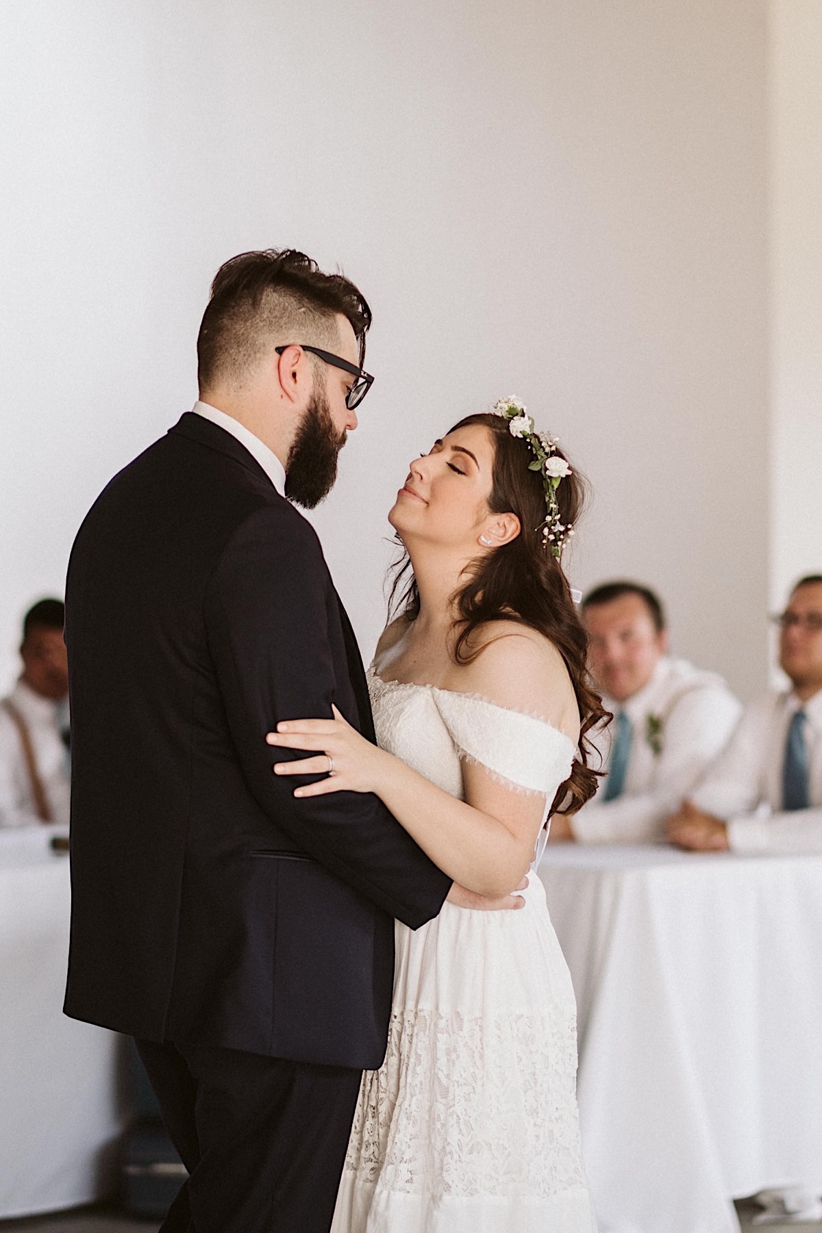 Husband and wife first dance under white string patio lights during wedding reception