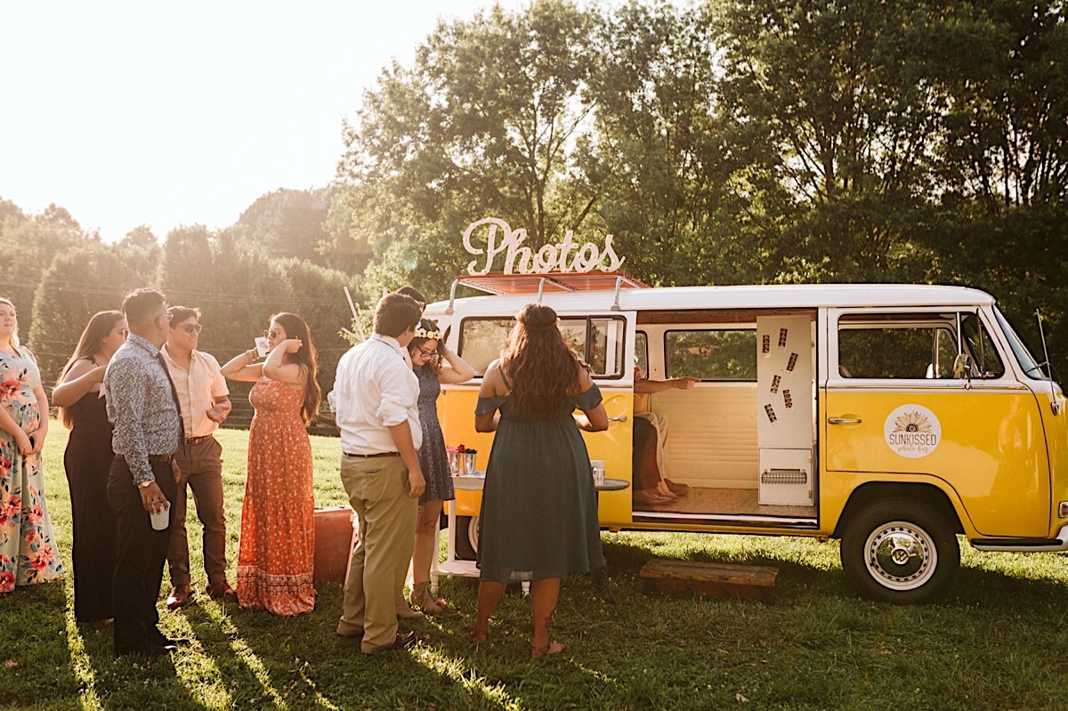 People line up for turns in a photo booth in the back seat of a Volkswagon van at a wedding at Creative Arts Guild in Dalton