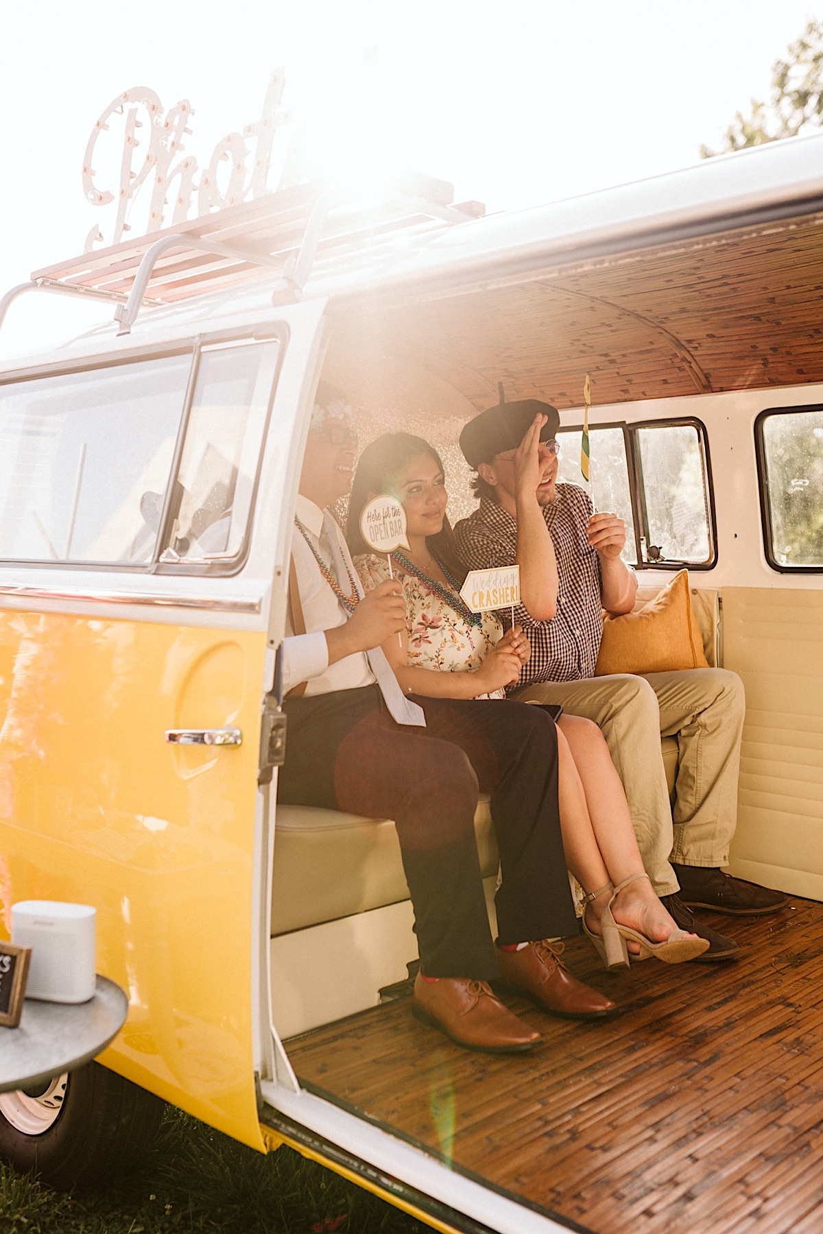 Three people sit in the back seat of a Volkswagon van-turned-photo booth at a wedding at Creative Arts Guild in Dalton, GA