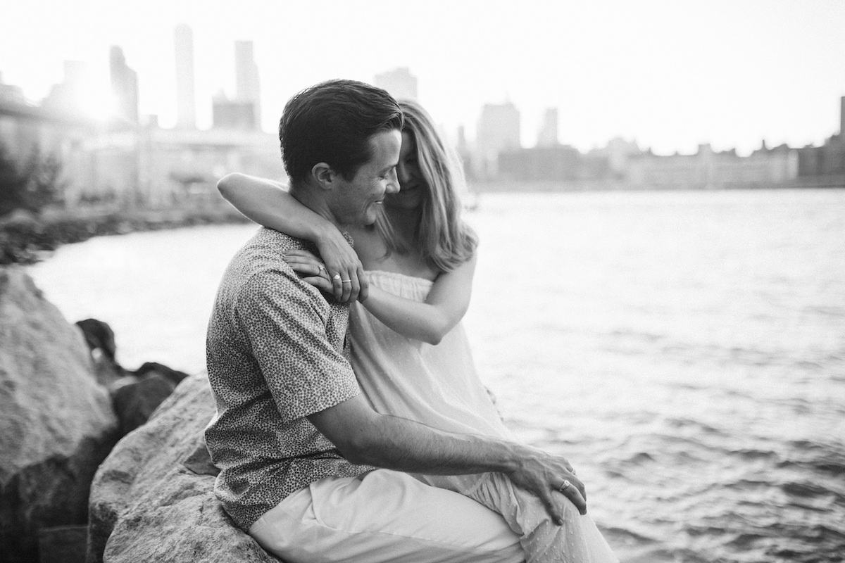 Man and woman cuddle on large rocks at the East River in New York City
