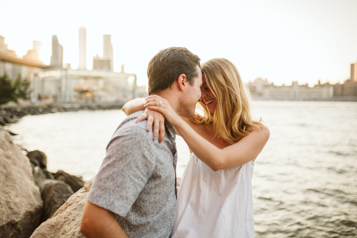 Man and woman cuddle on large rocks at the East River in New York City