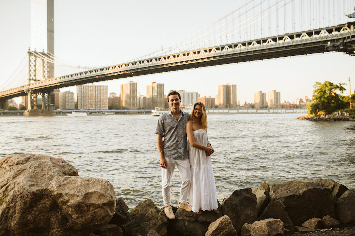 Man and woman holding each other under the Brooklyn Bridge during Dumbo Brooklyn engagement session