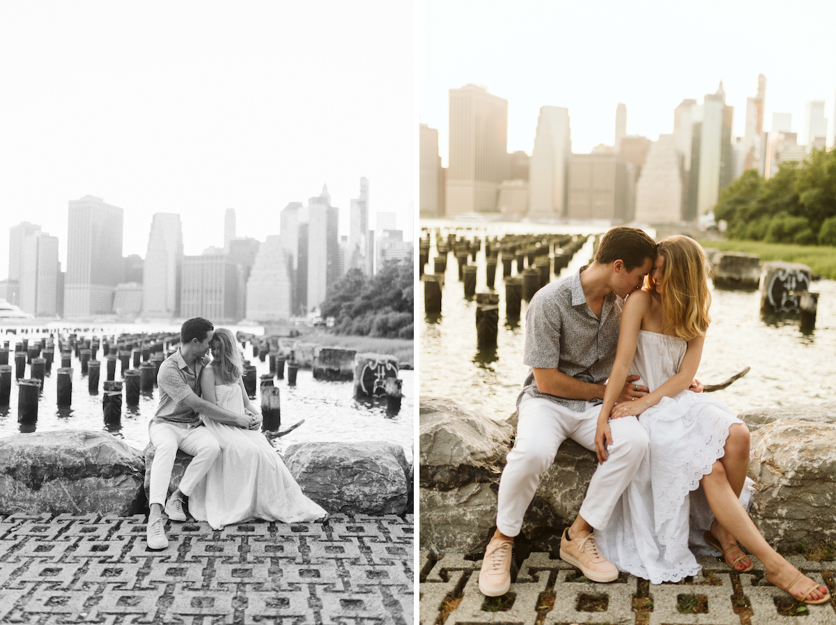 Man and woman cuddle on large rocks waterside with New York City scape in background
