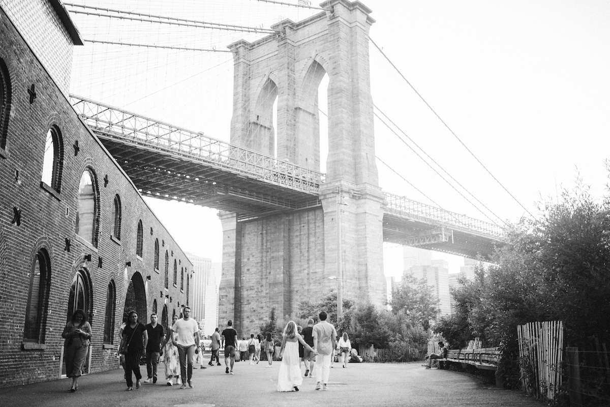 man and woman walking hand-in-hand toward the Brooklyn Bridge