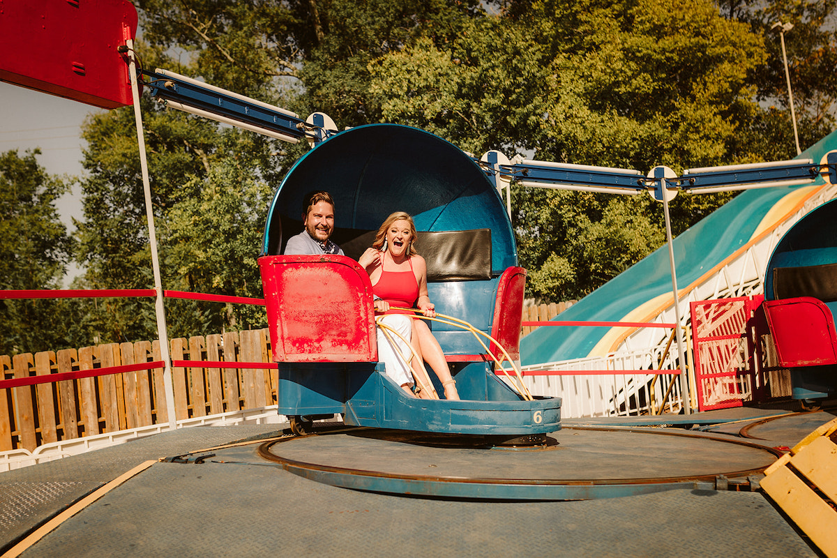 Man and woman laugh in blue and red spinning carnival ride