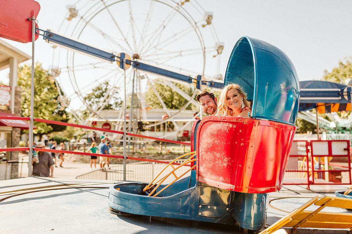 Man and woman ride a blue and red spinning carnival ride