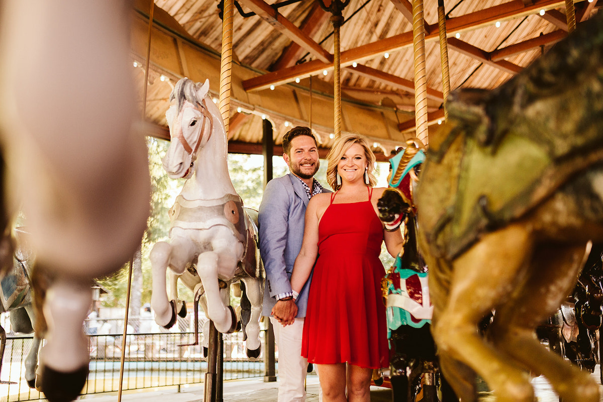 Man and woman stand between horses on Lake Winnie's carousel in Chattanooga, TN